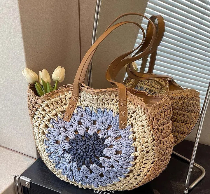 Colorful woven round tote bag made of straw with leather handles, featuring flowers, stylish beach accessory.