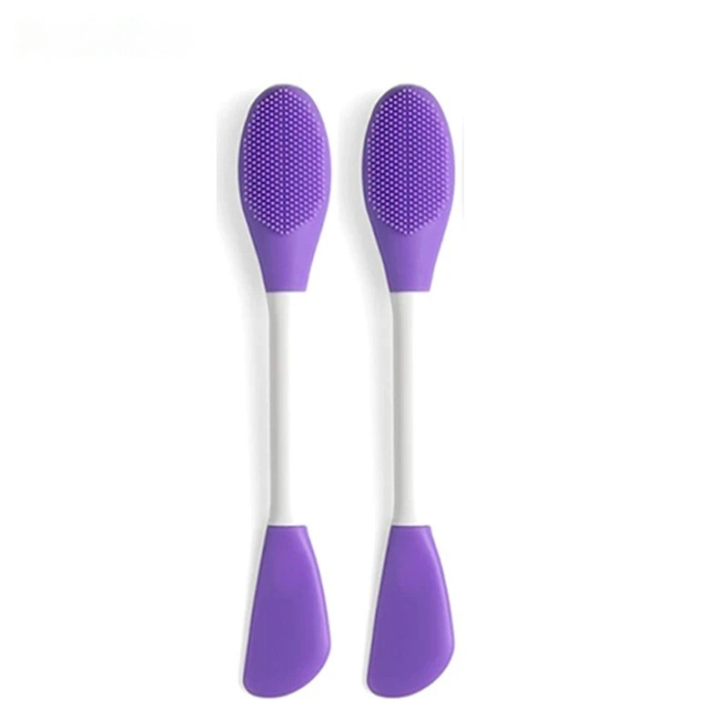 Two purple and white silicone face brushes on a white background