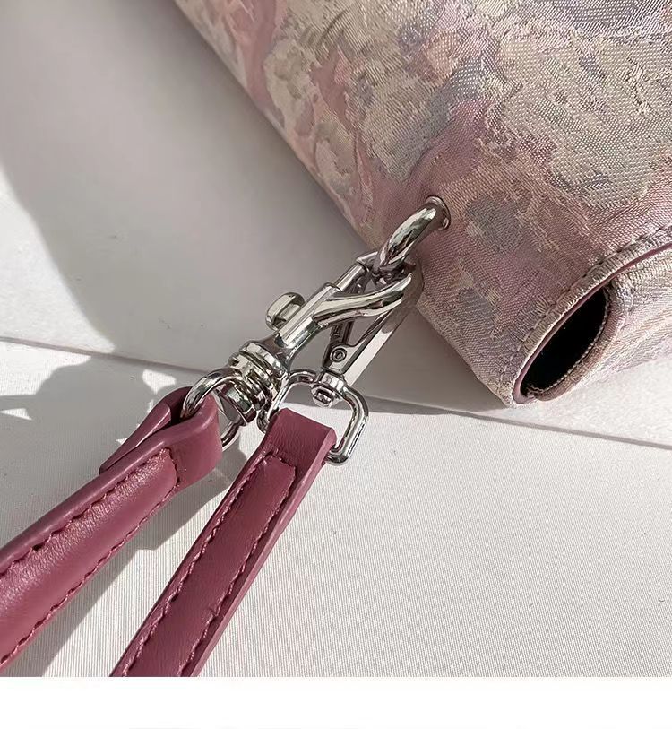 Close-up of a pink handbag with a silver clasp on a light background