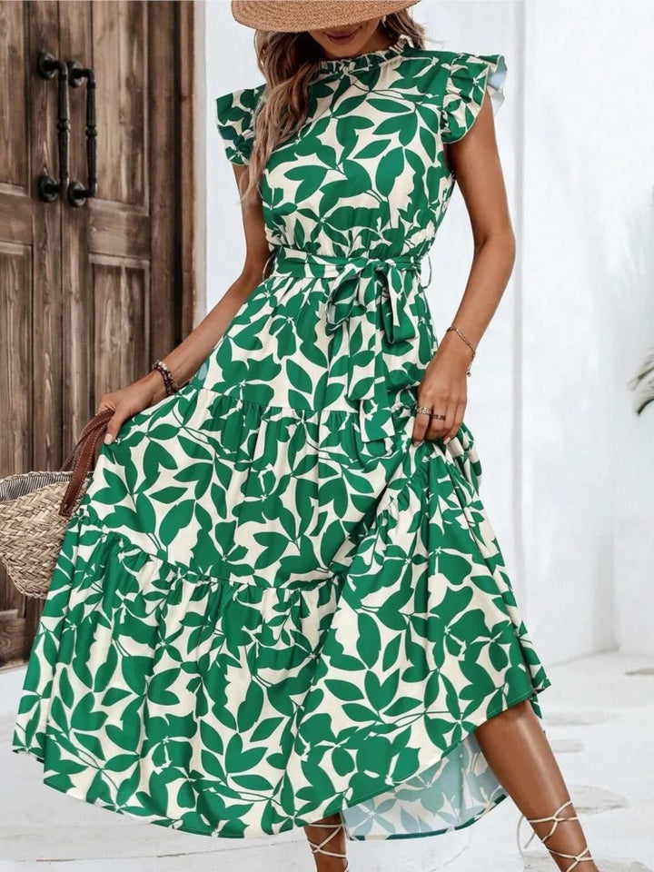 Woman wearing a green leaf-patterned dress indoors.