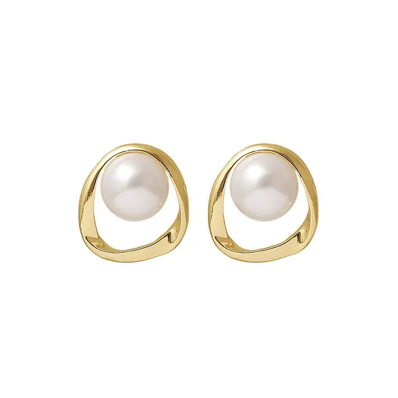 Pair of gold pearl drop earrings with pearl centers on a white background