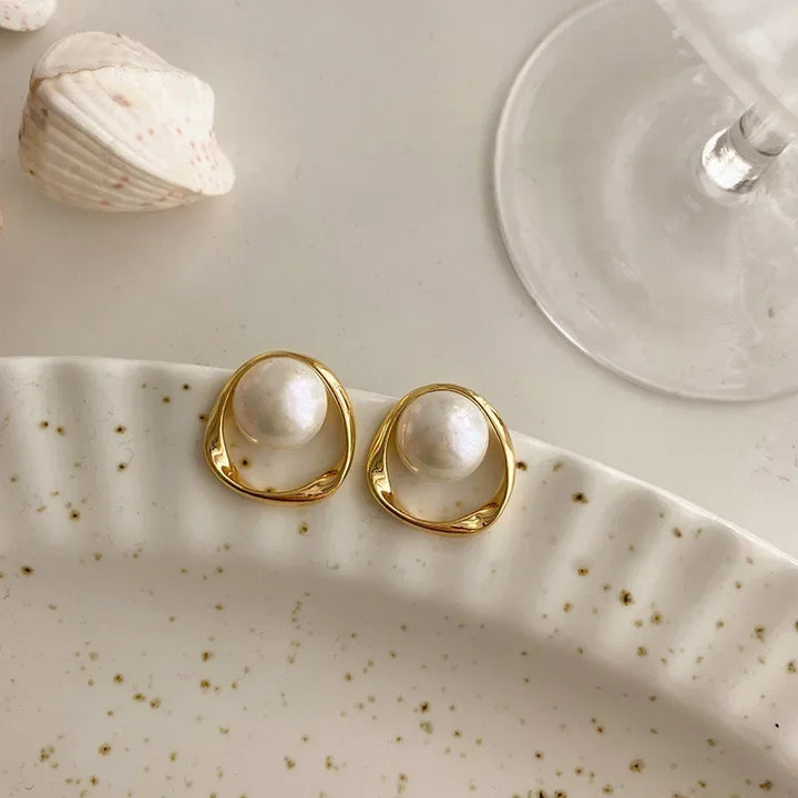 Gold pearl drop earrings on a table