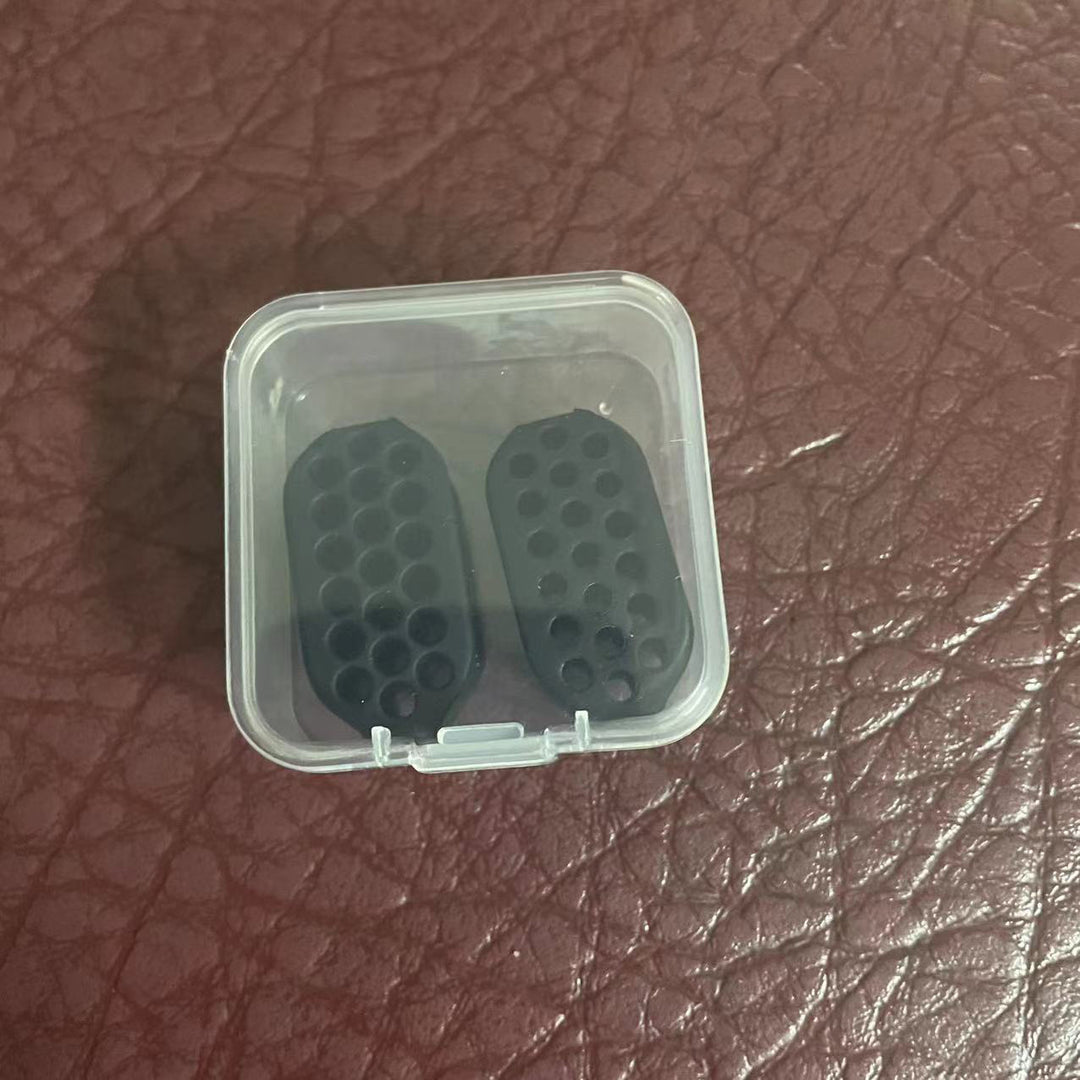 Two mini-jawline-exerciser in a clear plastic container on a brown leather surface