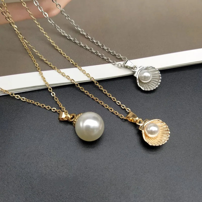 Two pearl necklaces with shell pendants  and a pearl necklace on a dark surface