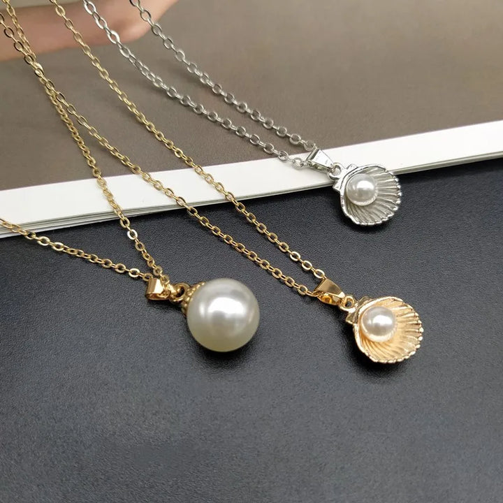 Two pearl necklaces with shell pendants  and a pearl necklace on a dark surface