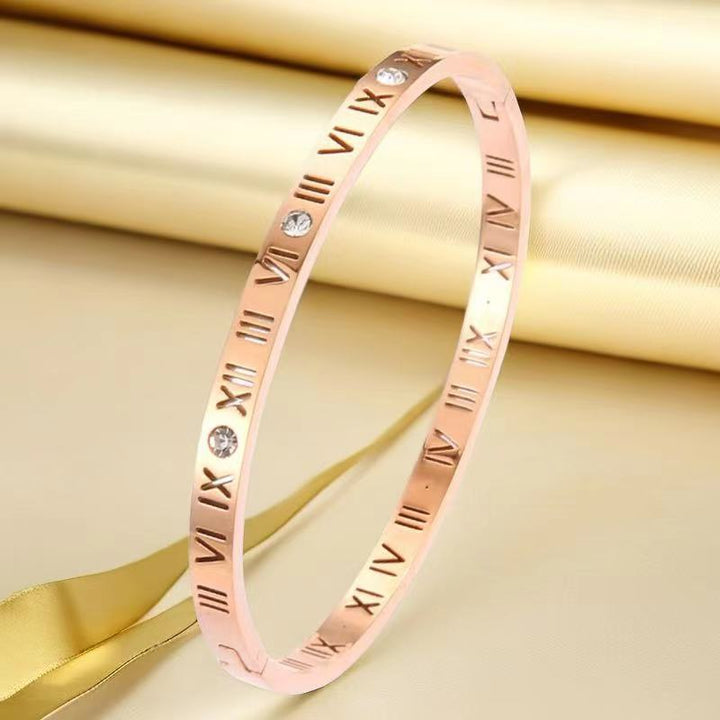 Elegant women's rose gold bracelet featuring Roman numerals and crystals against a luxurious gold background.