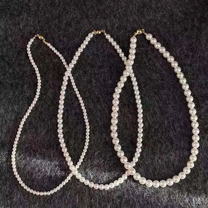 Three elegant white pearl necklaces displayed on a dark surface, showcasing different lengths and styles.