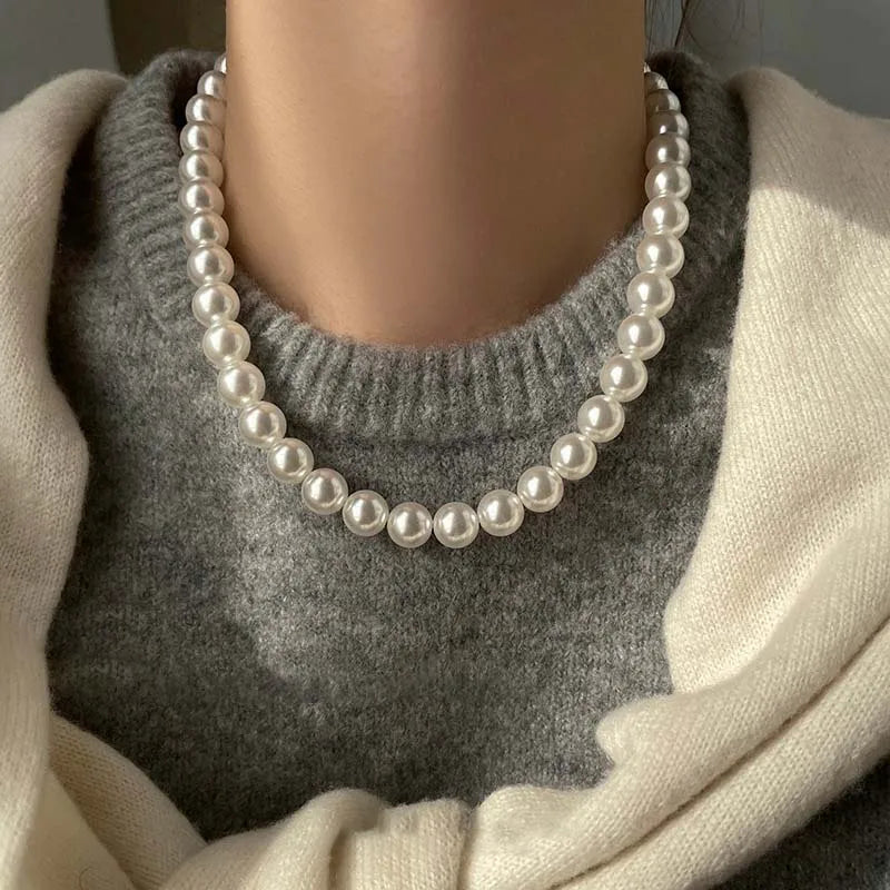 Elegant white pearl necklace worn on a gray sweater, showcasing a chic and timeless jewelry style.