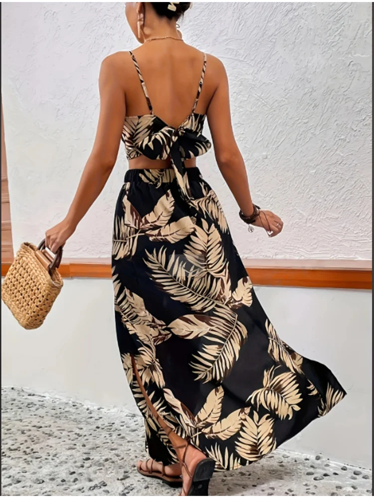 A woman wearing a black summer-printed vest and skirt set is holding a woven bag.
