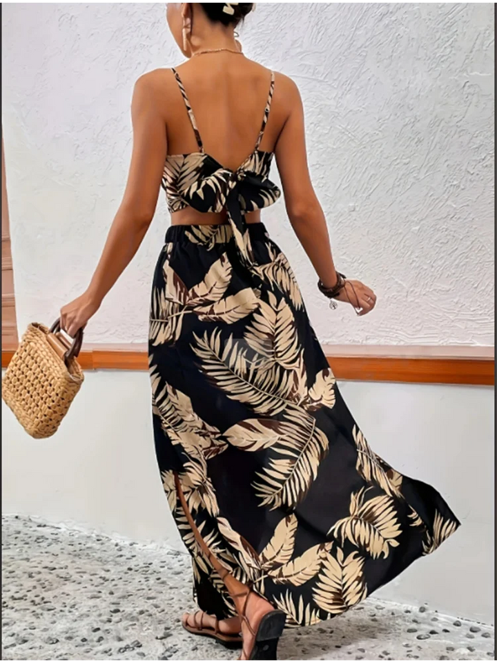 A woman wearing a black summer-printed vest and skirt set is holding a woven bag.