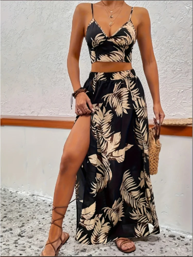 A woman stands on a stone surface, adorned in a black summer printed vest and skirt set.