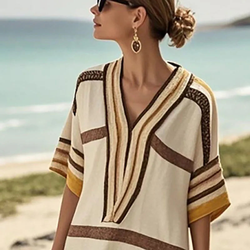 Woman wearing a vintage stripe print midi dress with stylish sunglasses by the beach.
