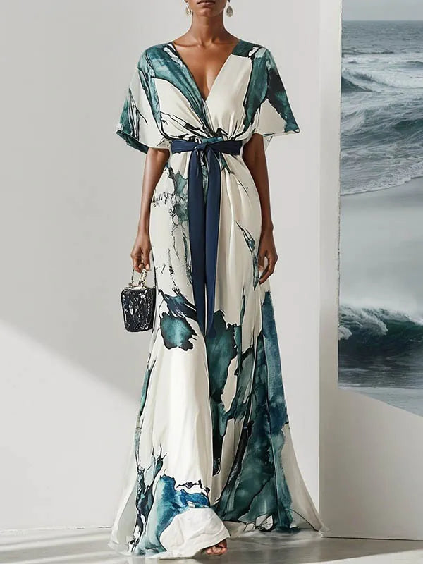 Woman wearing a watercolor dress with a blue belt in a minimalistic setting.