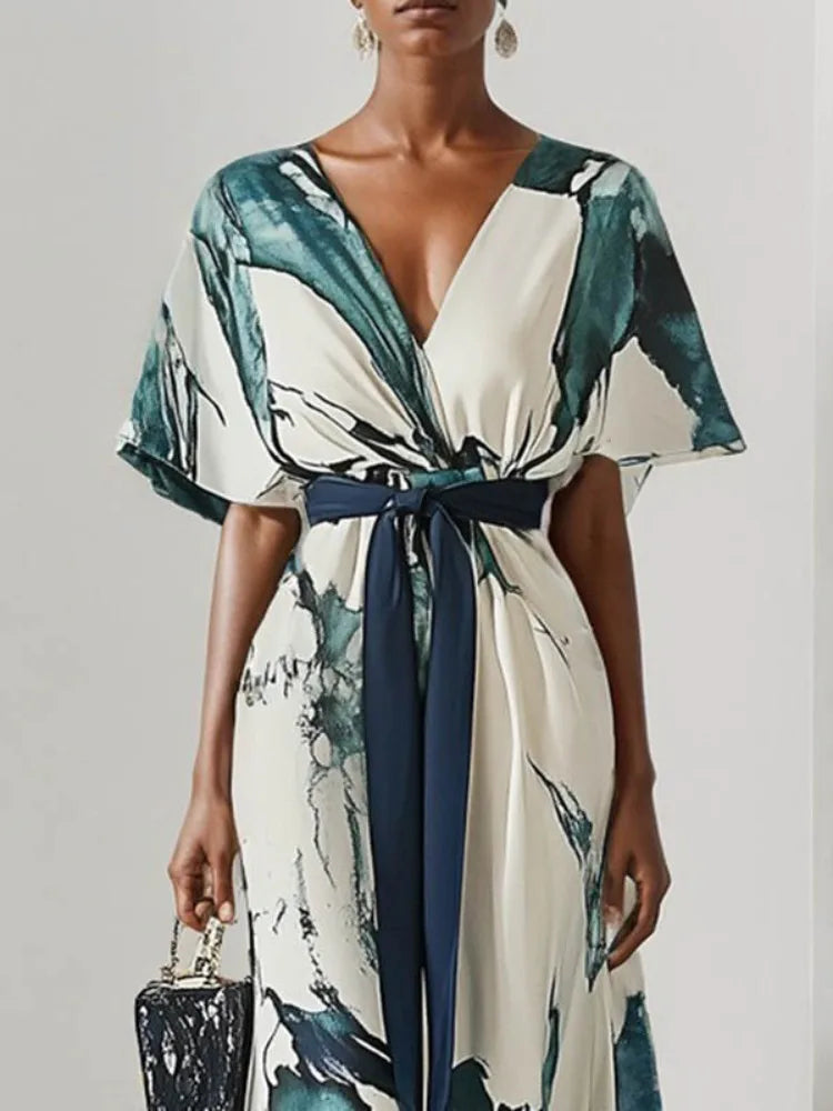Woman wearing a watercolor dress with a belt against a plain background